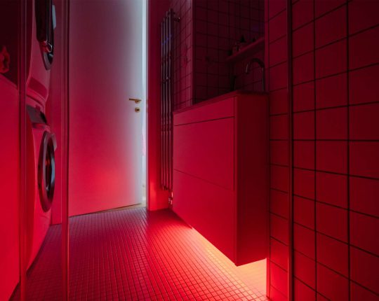 Odvažné červené podsvícení dodává koupelně na originalitě.