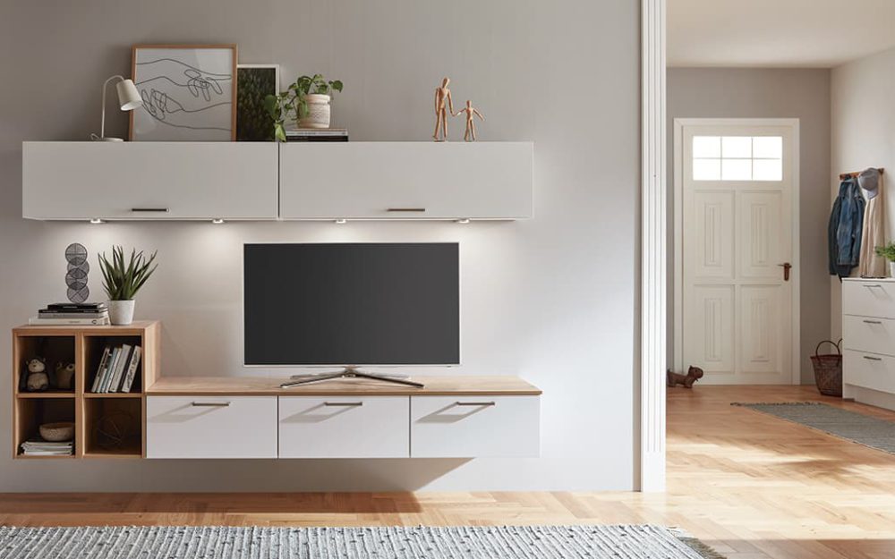 SIKO Bílá obýváková stěna s televizí, v kombinaci se světlými dřevěnými otevřenými policemi.