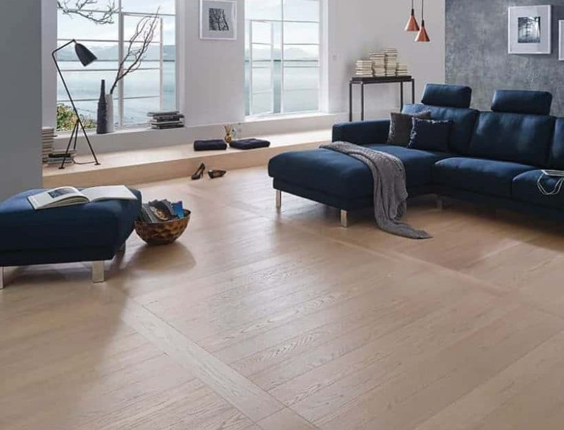 SIKO Moderní obývák s neobvyklou pokládkou dřevěné podlahy. Tmavěmodrý gauč a originální stěny ladí s dřevěnou podlahou.