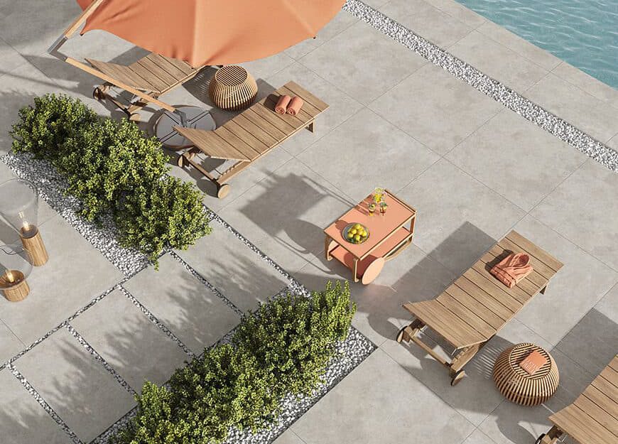 SIKO Okolí bazénu s lehátky a slunečníky, venkovní dlažba v pískové barvě v kontrastu se svěží zelení.