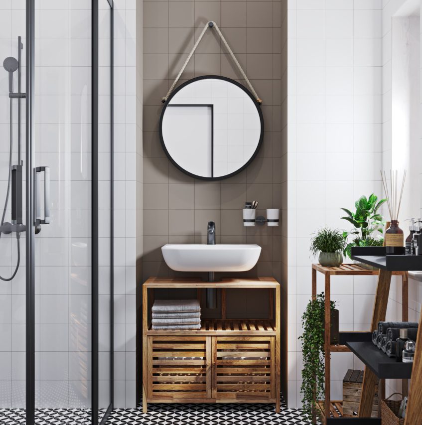 SIKO Moderná kúpeľňa s okrúhlym zrkadlom, drevenou skrinkou pod umývadlo, biele oblé umývadlo, sivý obklad, čiernobiela dlažba.