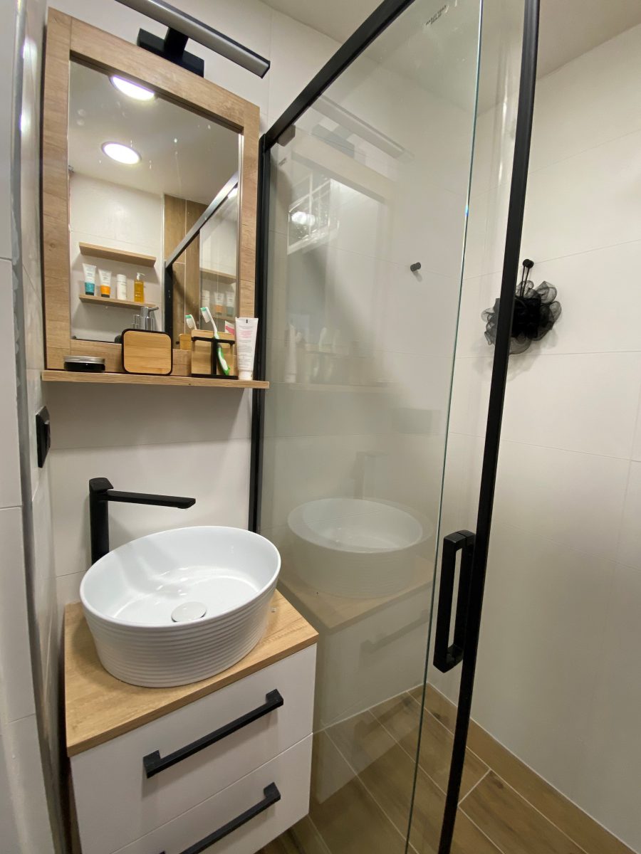 SIKO Malá kúpeľňa v nadčasovom dizajne drevo a biela, stavia na funkčnosti a praktickosti, nábytok na mieru, posuvné sprchové dvere.
