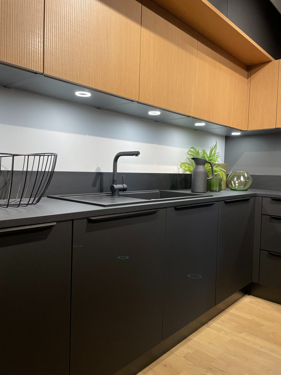 SIKO Čierna kuchyňa a výrazné drevené horné skrinky, podsvietená kuchyňa, drevená podlaha.