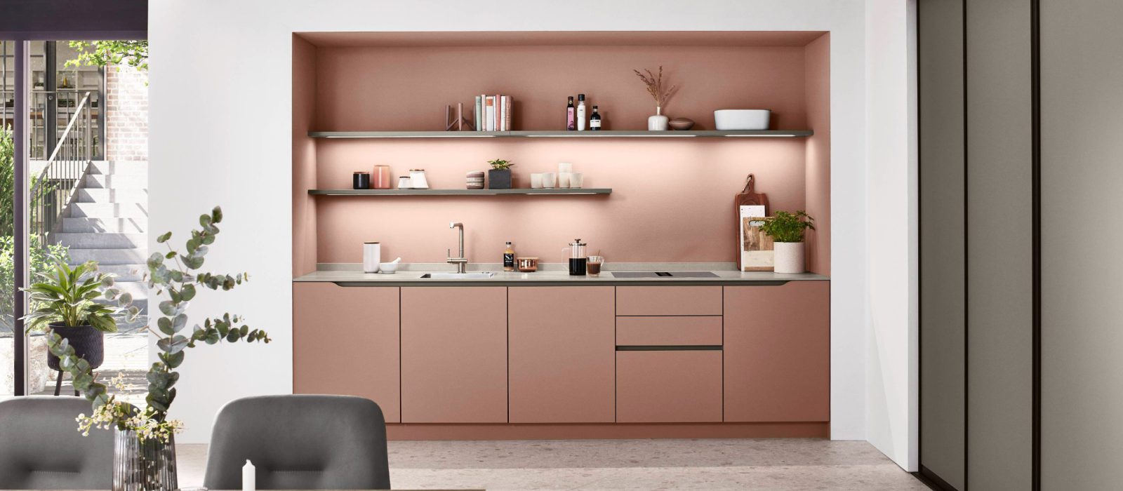 SIKO Nenápadná kuchyně v ružovém korálovém odstínu s vysokými posuvnými dveřmi vestavné úložné skříně v antracitové barvě.