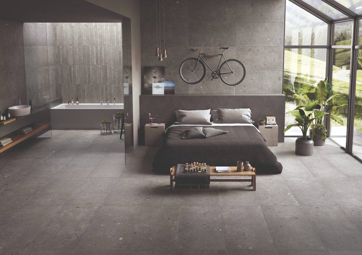 SIKO Šedá ložnice s koupelnou s obezděnou vanou v minimalistickém provedení, obklad a dlažba v designu betonu a kamene, obezděná vana, velká postel
