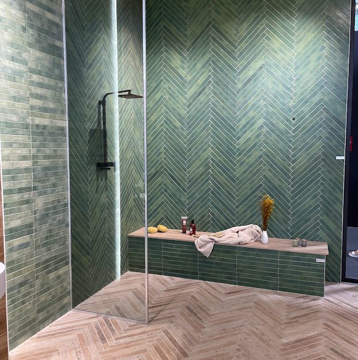 SIKO Trend moderní koupelna 2024 úzké formáty v parketovém designu v odstínu hnědá a zelená na podlaze i zdech, sprchový kout s odkládací plochou