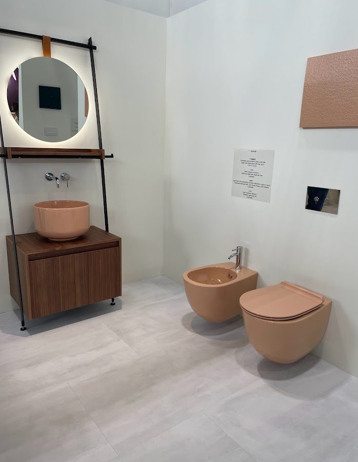 SIKO Trendy moderní koupelna 2024 cementové a šedé tóny v kontrastu s barevnou koupelnovou keramikou v cihlové barvě - umyvadlo, toaleta i bidet