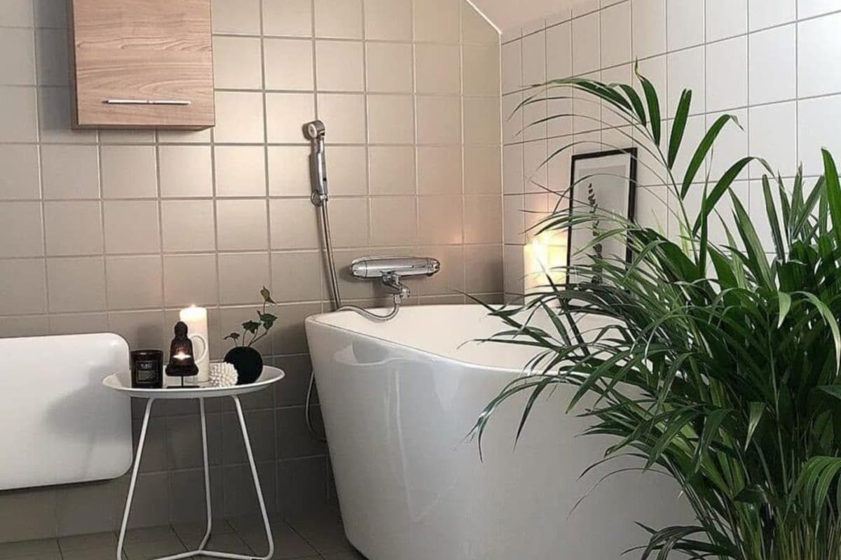 SIKO Podkrovná kúpeľňa vykurovaná sálavým teplom z bieleho vykurovacieho panelu, voľne stojaca vaňa a štvorcové svetlé obklady.