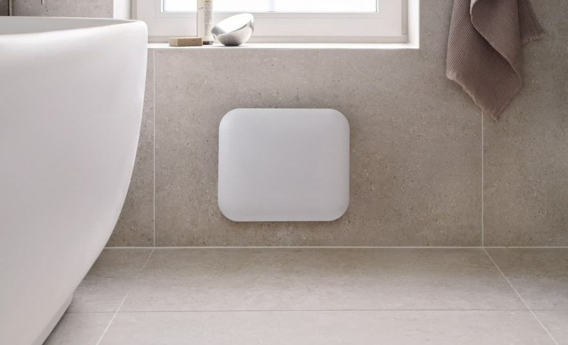 SIKO_Malý bílý topný panel pro příjemné teplo v koupelně. Obklad a dlažba v designu kamene, volně stojící vana.